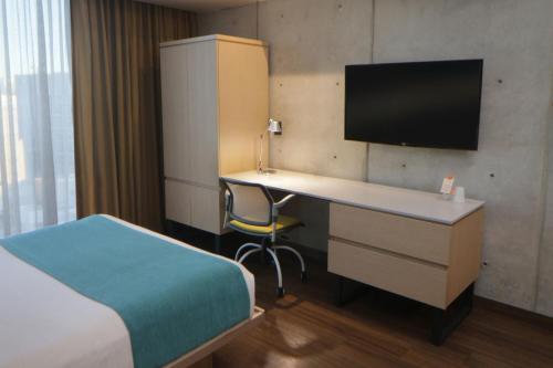 a hotel room with a desk and a bed and a tv at City Express Suites by Marriott Tijuana Rio in Tijuana