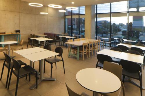 a dining room with tables and chairs and windows at City Express Suites by Marriott Tijuana Rio in Tijuana
