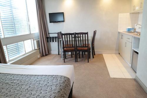a room with a kitchen and a table and chairs at Parkville Place Serviced Apartments in Melbourne
