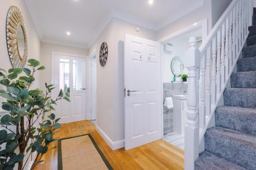 a white hallway with stairs and a door with a mirror at NEW! Incredible Home In Northwich By 53 Degrees Property, Perfect For Groups, FREE Parking! in Northwich