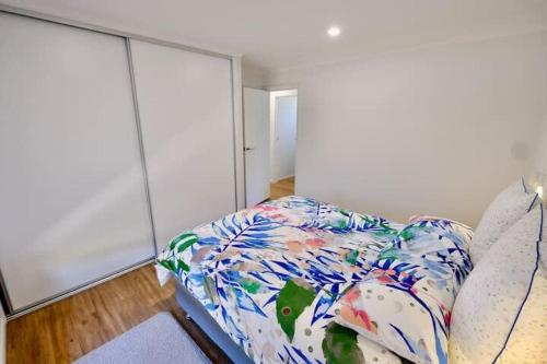 a bedroom with a bed with a floral comforter at Beach House with Sea Views and a Large Backyard in Devonport