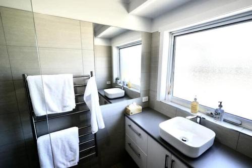 a bathroom with a sink and a mirror and a window at Beach House with Sea Views and a Large Backyard in Devonport