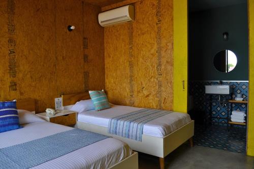 two beds in a room with yellow walls at Hotel Momotus Tuxtla - Desayuno opcional in Tuxtla Gutiérrez