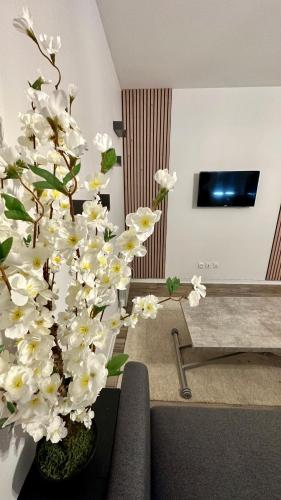 wazon wypełniony białymi kwiatami w salonie w obiekcie Le Nouveau des Ponts w mieście Vierzon