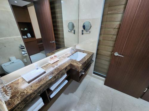 a bathroom with a sink and a large mirror at Ramada by Wyndham Jeju Hamdeok in Jeju