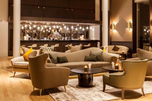 a lobby with couches and tables and a bar at AC Hotel by Marriott Paris Le Bourget Airport in Le Bourget