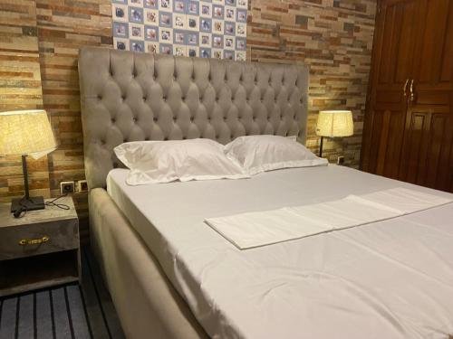 een slaapkamer met een groot wit bed met 2 lampen bij Appartement K.N.Y in Yaoundé