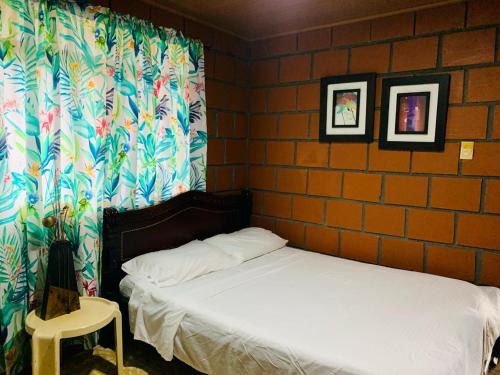 1 dormitorio con cama y pared de ladrillo en Finca turística VILLA OFELIA, en Quimbaya