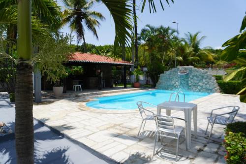 patio ze stołem i krzesłami przy basenie w obiekcie Casa do Sol na Reserva do Paiva w mieście Cabo de Santo Agostinho