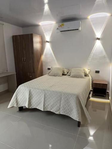 Apartaestudio en Barranquilla في بارانكويلا: غرفة نوم بسرير وملاءات بيضاء واضاءات