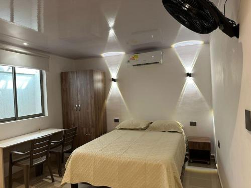 Apartaestudio en Barranquilla في بارانكويلا: غرفة نوم بسرير ومكتب مع كراسي