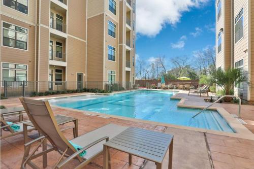 a swimming pool in a apartment complex with chairs and a table at The Alexan* Walk to NRG* TX Med Center* Downtown in Houston
