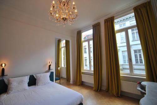 a bedroom with a bed and two windows and a chandelier at Upstairs in Antwerp