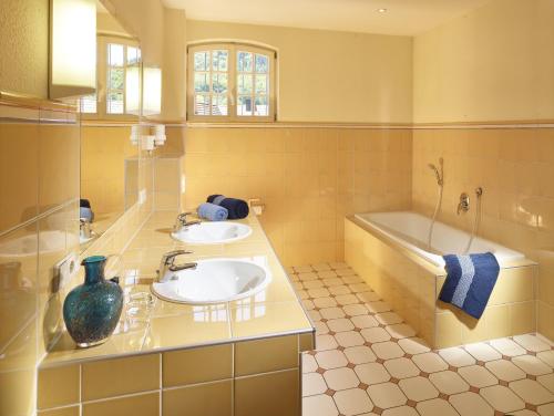 a bathroom with two sinks and a bath tub at Hotel & Restaurant Burgschänke in Kaiserslautern