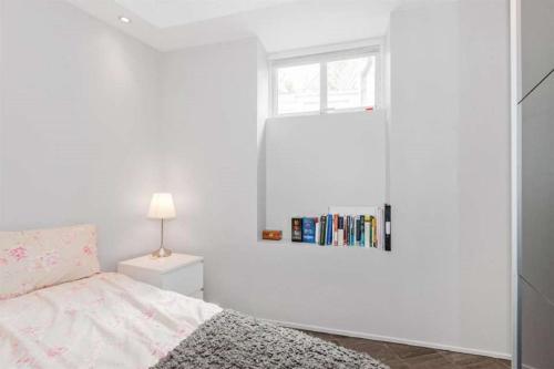 a white bedroom with a bed and a window at Pepes Apartment in Bergen