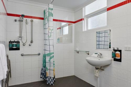 uma casa de banho com um lavatório e um chuveiro em Baileys Parkside Motel by VetroBlu em Perth