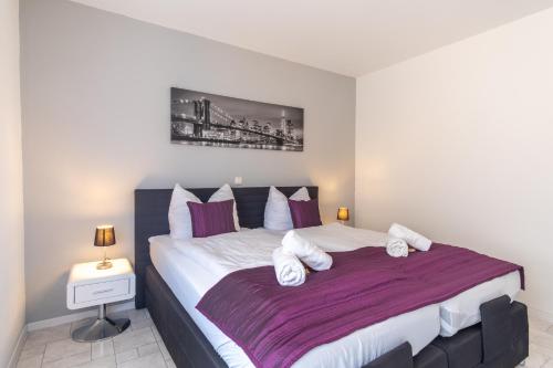 a bedroom with a large bed with purple and white pillows at Arbeitsplatz, Balkon, Tiefgarage nähe neue Messe in Leipzig
