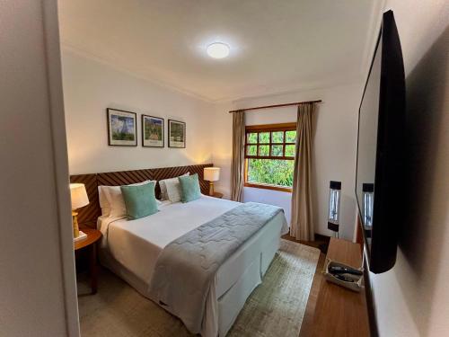 a hotel room with a bed and a television at Casa Três Rios - Campos do Jordão in Campos do Jordão