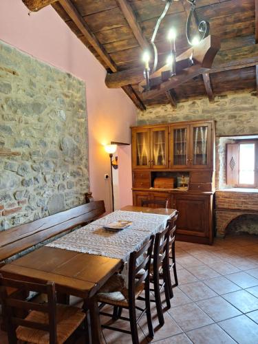 jadalnia ze stołem i kamienną ścianą w obiekcie Agriturismo Ristoro del Cavaliere w mieście Piazza al Serchio