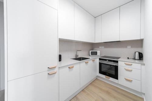 a white kitchen with white cabinets and appliances at Residence Mozaika in Prague