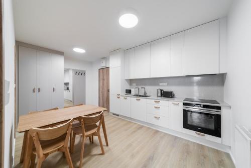 a kitchen with white cabinets and a wooden table and chairs at Residence Mozaika in Prague