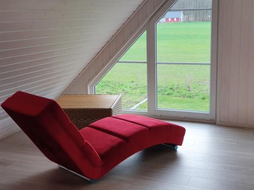 uma cadeira vermelha num quarto com uma grande janela em Haus Feldblick am Wasser em Berg