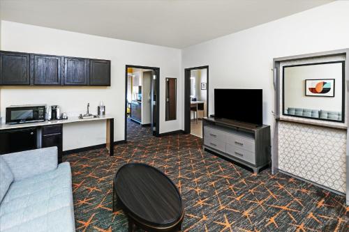 a living room with a couch and a flat screen tv at Holiday Inn Hotel & Suites Tulsa South by IHG in Tulsa