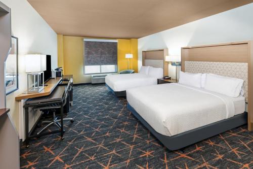 Holiday Inn Hotel & Suites Tulsa South, an IHG Hotel في تولسا: غرفة فندقية بسريرين ومكتب