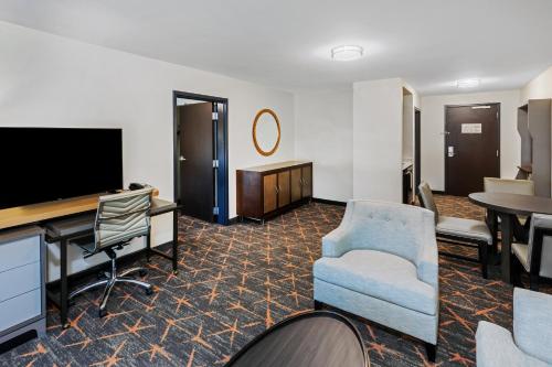 a hotel room with a tv and a chair and a table at Holiday Inn Hotel & Suites Tulsa South by IHG in Tulsa