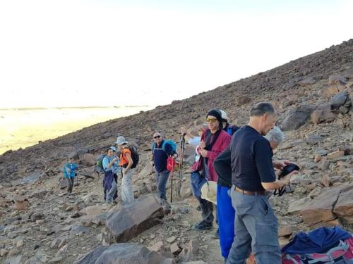 a group of people walking on a rocky mountain at GITE Take your time in Merzouga