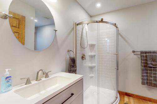 uma casa de banho com um lavatório e um chuveiro com um espelho. em Vineyard Sanctuary em Penn Yan