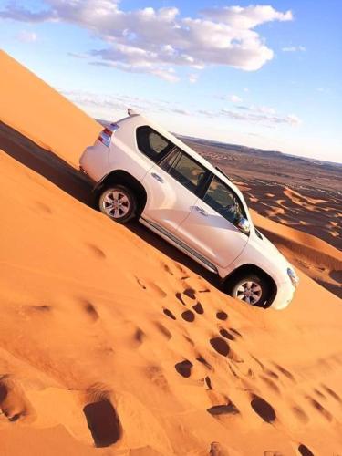 a car driving in the sand in the desert at GITE Take your time in Merzouga