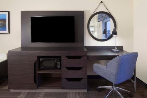 a living room with a tv and a chair and a mirror at Hampton Inn Charleston-Southridge in Charleston