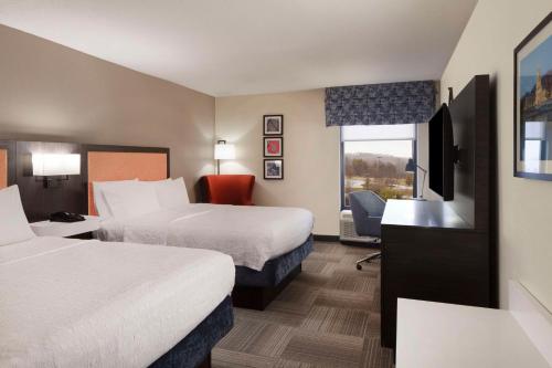 a hotel room with two beds and a television at Hampton Inn Charleston-Southridge in Charleston