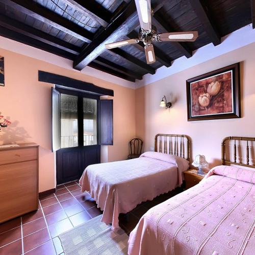 a bedroom with two beds and a ceiling fan at Casa Tia Emilia in Villar de Plasencia