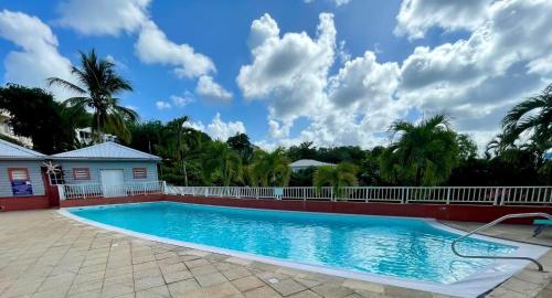 ein Pool vor einem Haus mit Palmen in der Unterkunft La Caravelle - Agréable studio vue sur mer avec piscine in La Trinité