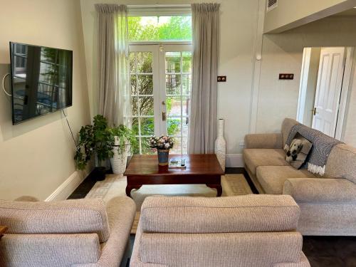 a living room with two couches and a table at Porters Cottage Garden in Albury
