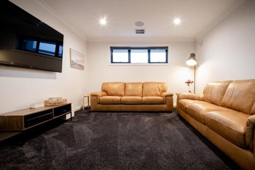 a living room with two leather couches and a flat screen tv at Modern Home for Large Groups or Families in Newstead