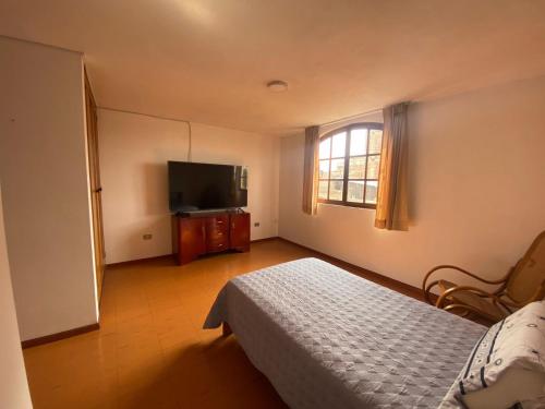 um quarto com uma cama e uma televisão de ecrã plano em Casa Zela em Yanahuara