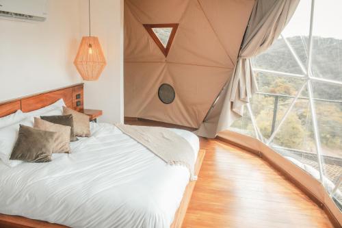 ein Schlafzimmer mit einem Bett und einem großen Fenster in der Unterkunft Ananta Forest - Glamping Dome - Hot Tub - Sunset & Gulf View in Monteverde Costa Rica