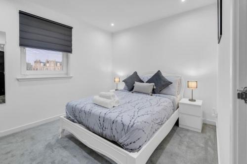a white bedroom with a bed and a window at Hellena Lodge in Aberdeen