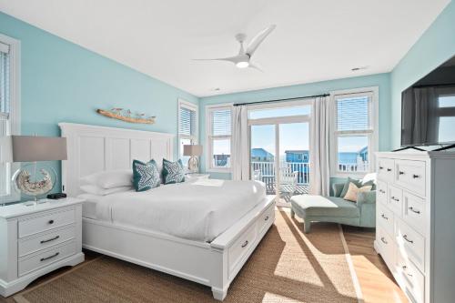 1 dormitorio con cama blanca y pared azul en Coastal Vista - Walk to Emerald Isle Beach!, en Emerald Isle