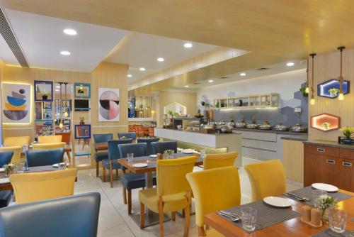 a restaurant with tables and chairs and a kitchen at Hampton by Hilton Vadodara-Alkapuri in Vadodara