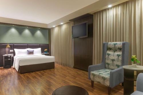 sypialnia z łóżkiem, krzesłem i telewizorem w obiekcie Hampton by Hilton Vadodara-Alkapuri w mieście Vadodara
