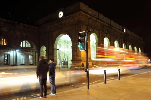 two people standing next to a traffic light in front of a building at Hampton by Hilton Newcastle in Newcastle upon Tyne