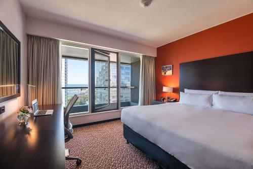 a hotel room with a bed and a desk and windows at Hilton Garden Inn Montevideo in Montevideo