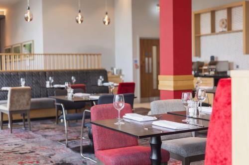 un restaurante con mesas y sillas y copas de vino en Hilton Garden Inn Birmingham Airport Uk en Bickenhill