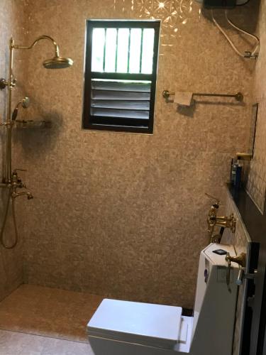 a bathroom with a toilet and a window at Saman Villa in Kadawata