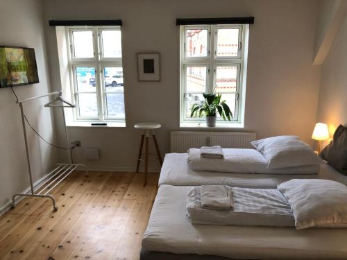 two beds in a room with two windows at Huset ved springvandet in Randers