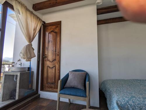 a bedroom with a bed and a chair and a sink at Vista Volcan in Antigua Guatemala